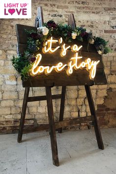 a sign that says it's a love story with flowers and greenery on top