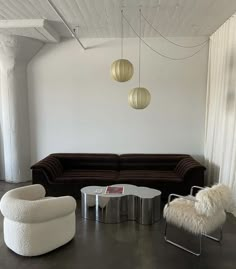 a living room filled with furniture and two lamps hanging over the top of it's walls