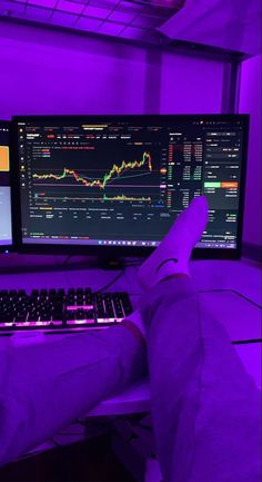 a person is sitting in front of a computer monitor with their feet on the keyboard