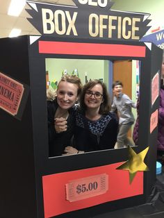 two women and a child are posing for a photo in a cardboard box office booth