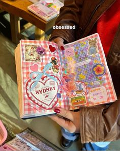 a person holding an open book with stickers on it and other items in the background