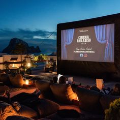 people sitting on couches in front of a movie screen at night with candles lit up