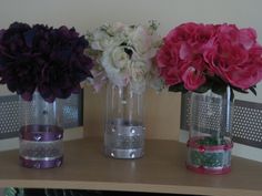 three vases with flowers in them sitting on a table