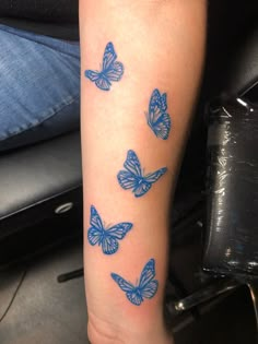 blue butterflies are on the arm of a person