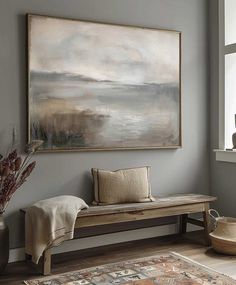 a painting hanging on the wall above a bench in a room with a rug and pillows