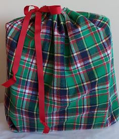 a green and red plaid bag with a red ribbon on the top is sitting on a white surface