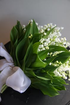 a bouquet of white flowers sitting on top of a black table next to a wall