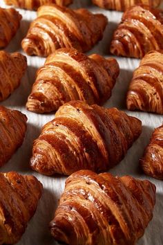 many croissants are lined up on a baking sheet