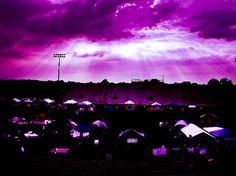 the sky is filled with purple clouds and tents