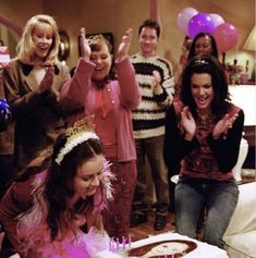 a group of people standing around a birthday cake