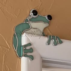 a frog is sitting on the edge of a door frame with its eyes wide open