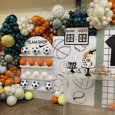 a room filled with lots of balloons and soccer themed decorations on the wall behind it