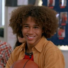 a young man with curly hair holding a basketball