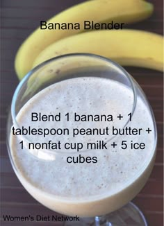 a banana and tablepoon peanut butter smoothie in a glass next to some bananas