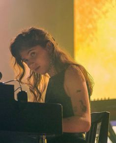 a woman with long hair sitting at a table in front of a keyboard and microphone