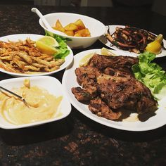 a table topped with white plates filled with different types of food and dipping sauces