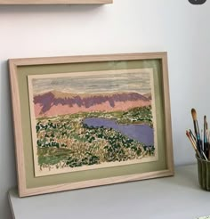 a painting is hanging on the wall next to a cup with paintbrushes in it