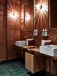 a bathroom with two sinks and three lights on the wall above them in wood paneling