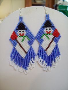 a pair of blue and white beaded earrings with snowman on it's face