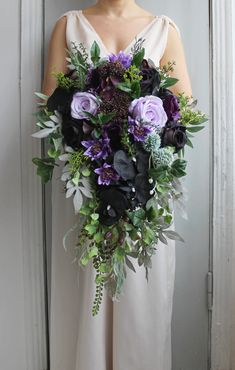 a woman holding a bouquet of flowers in her hands and wearing a white dress with purple accents