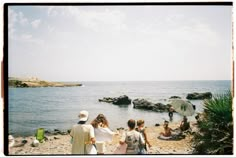 some people are standing on the beach by the water