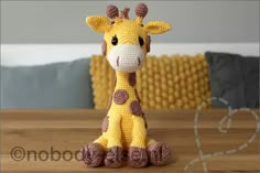 a crocheted giraffe sitting on top of a wooden table