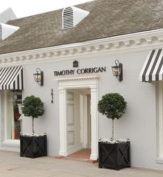 a white building with black and white awnings on it's front door