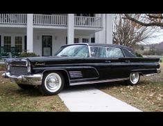 an old black car parked in front of a house