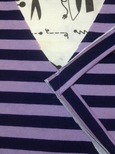 a purple and black striped shirt with penguin on it's collar, next to a piece of fabric