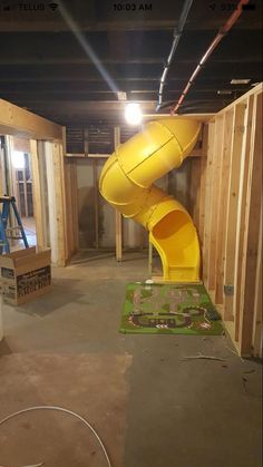 a yellow slide in the middle of a room with unfinished walls and wood framing around it