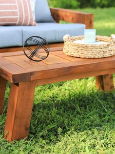 a wooden table sitting on top of a lush green field next to a blue couch