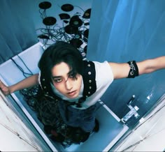 a man with black hair and piercings standing in front of a mirror