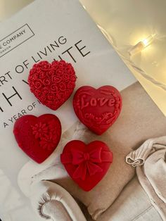 three red heart shaped buttons sitting on top of a white chair next to a book