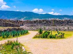 a dirt road in the middle of a stone walled area with mountains in the background