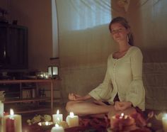 a woman sitting on the floor in front of candles