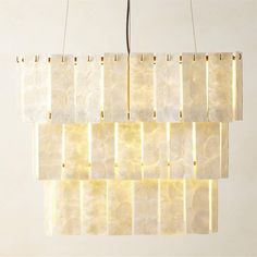 a rectangular light fixture hanging from a ceiling with white and gold strips on the sides