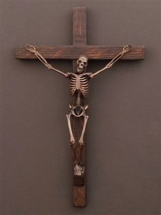 a wooden crucifix with a skeleton hanging from it's side on a wall