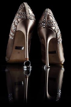 a pair of high heeled shoes sitting on top of a reflective surface with a ring in the middle