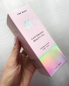 someone is holding up a pink box with the word, customized beauty oil on it