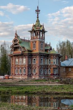 an old building with a clock tower on it's roof next to a body of water