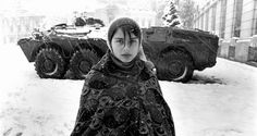 a woman standing in the snow next to tanks