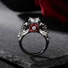 a close up of a ring with a rose on the center and two diamonds in the middle