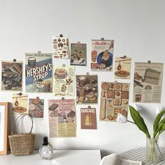 a white table topped with lots of pictures and posters on the wall next to a vase filled with flowers