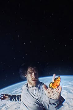 a man with a butterfly on his hand in front of the earth's surface