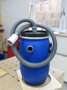 a large blue barrel with a hose attached to it sitting on top of a wooden table