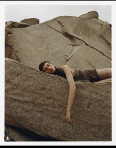 a woman laying on top of a large rock