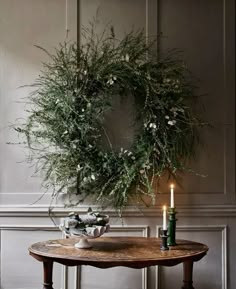 a table with a wreath and candles on it