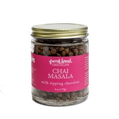 a glass jar filled with chocolate beans on top of a white table next to a pink label