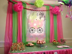 a table topped with lots of desserts under a pink and green drape covered window