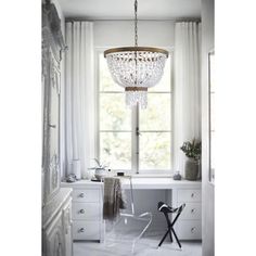 a chandelier hanging from the ceiling in front of a white desk and chair